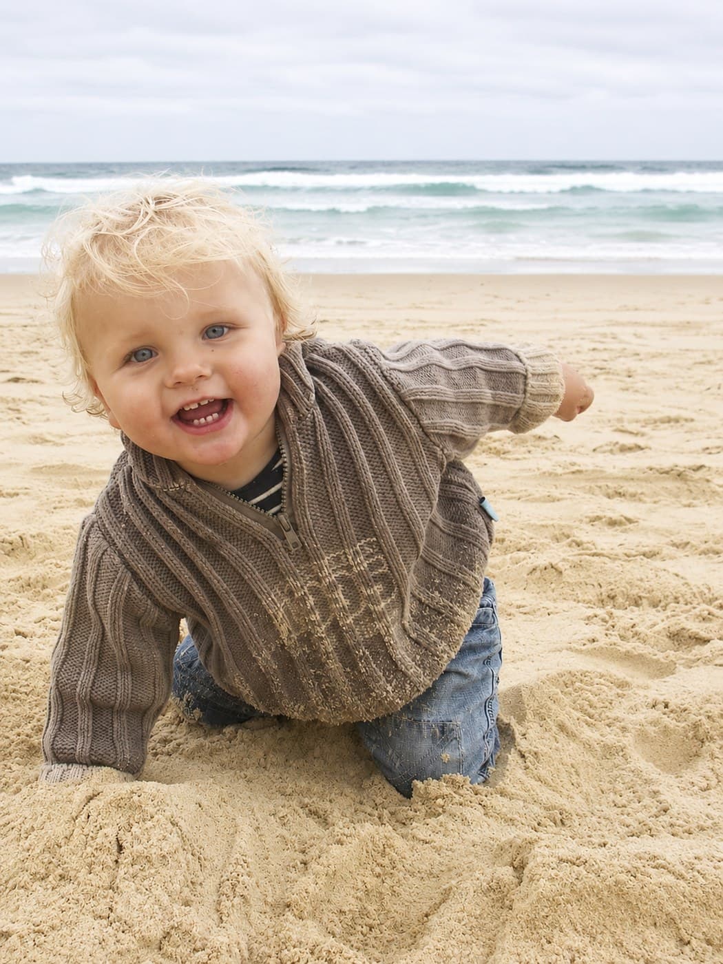 Lachende baby kruipt op het strand - eerste fase van openheid en verbondenheid