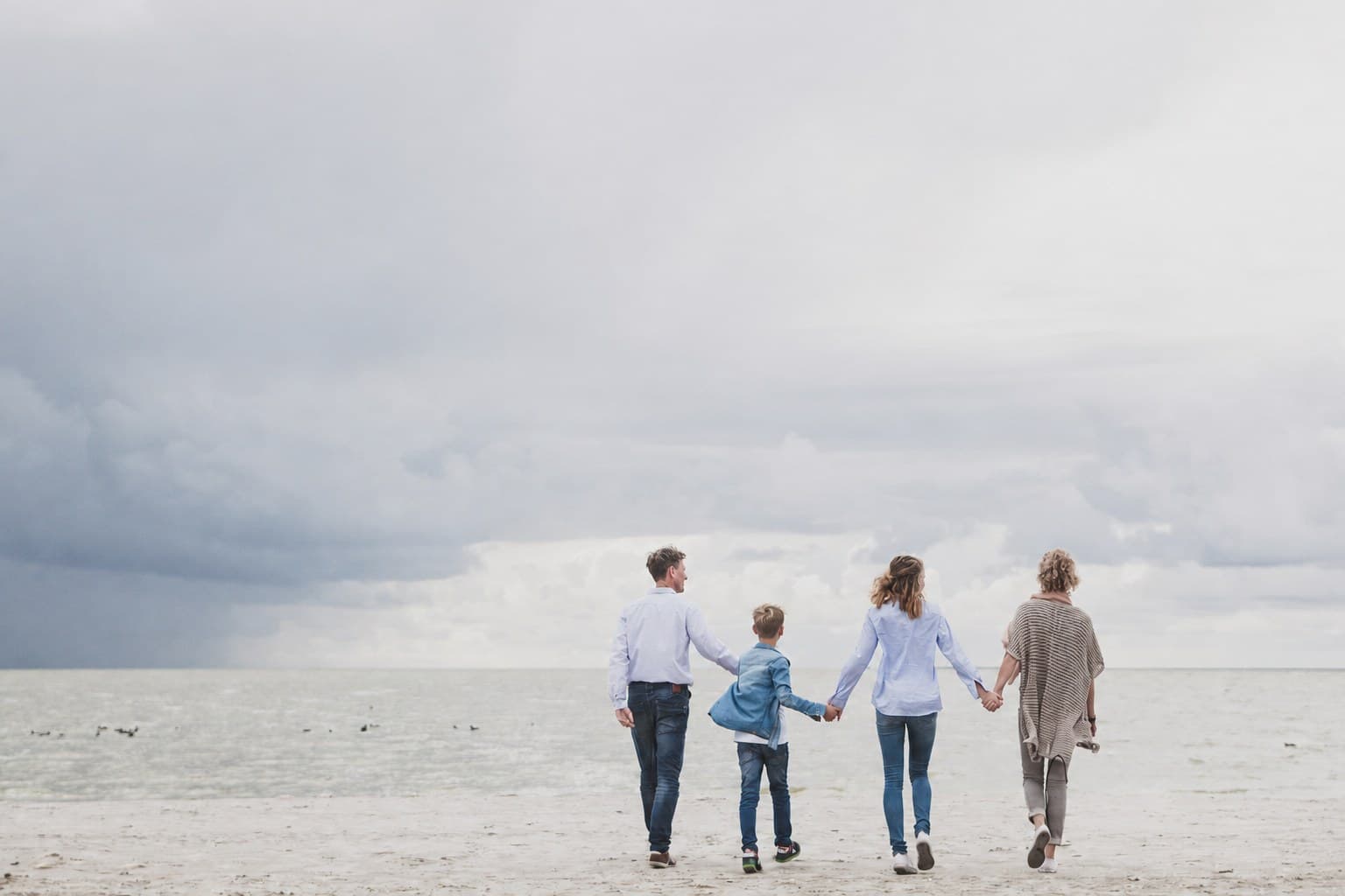 Gezin loopt hand in hand op het strand
