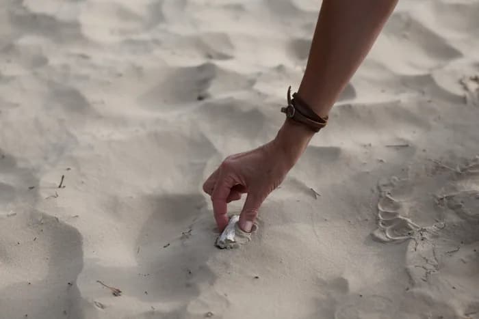 Hand zoekt een kleine vondst in het zand
