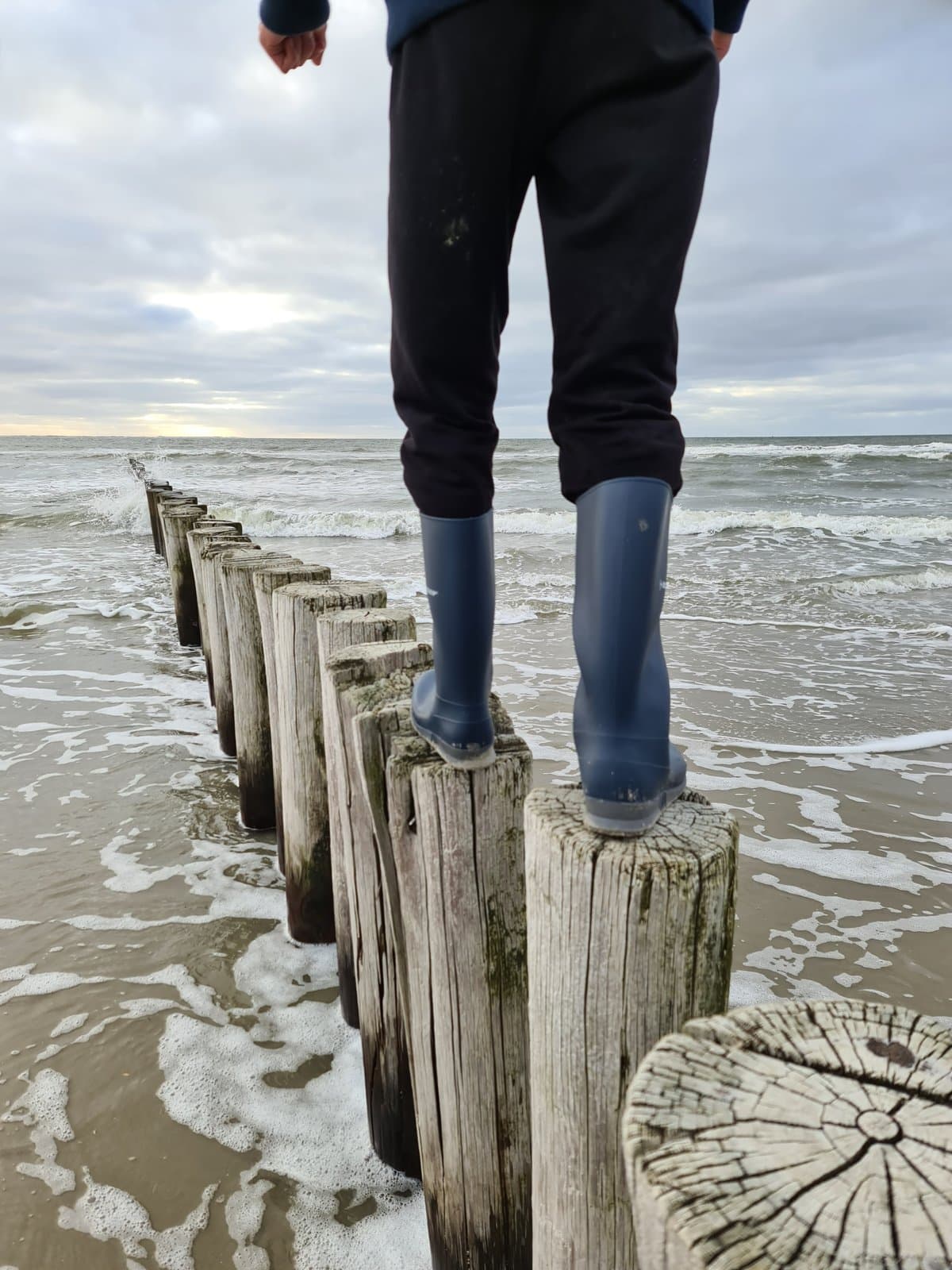 Iemand staat op een paalhoofd in zee - balans tussen geven en ontvangen