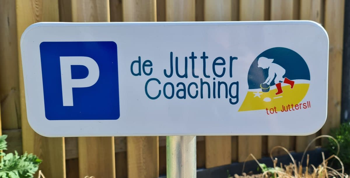 Parkeerbordje met logo van de Jutter Coaching naast de schuttingdeur